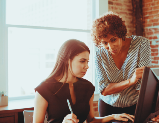 Mentor guiding colleague on project at modern office workspace.
