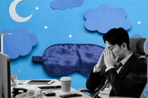 Office worker sitting at his desk, visibly tired and rubbing his eyes.