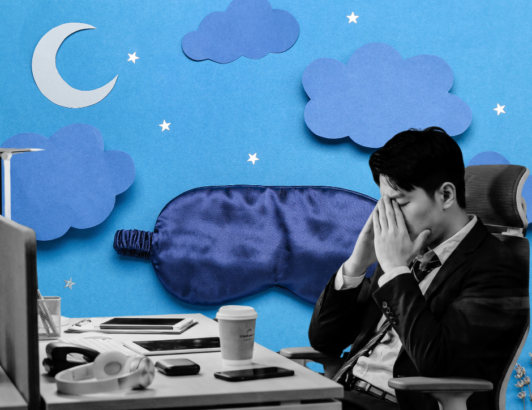 Office worker sitting at his desk, visibly tired and rubbing his eyes.